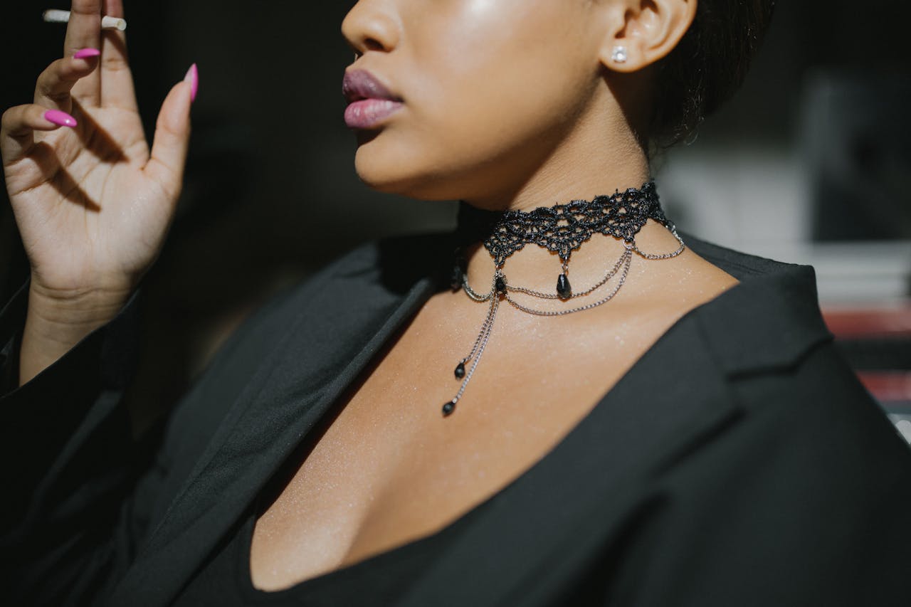 Close-up of a stylish woman in a black top smoking a cigarette, showcasing jewelry.